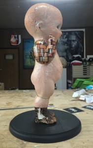 Haroshi -  <strong>Still Standing Despite the Odds (side)</strong> (2016<strong style = 'color:#635a27'></strong>)<bR /> composition doll, skateboard, wood,
12.59 x 5.51 x 4.33 inches,
(32 x 14 x 11 cm)