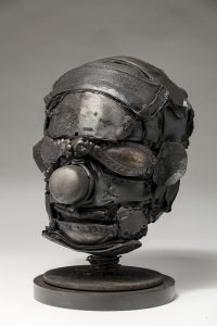 Ronald Gonzalez -  <strong>Mask (side)</strong> (2018<strong style = 'color:#635a27'></strong>)<bR /> black leather, found objects, wire, wax, carbon, screws and metal filings over welded steel armatures,
10 x 8 x 8 inches