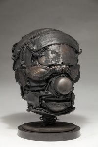 Ronald Gonzalez -  <strong>Mask (side)</strong> (2018<strong style = 'color:#635a27'></strong>)<bR /> black leather, found objects, wire, wax, carbon, screws and metal filings over welded steel armatures,
10 x 8 x 8 inches