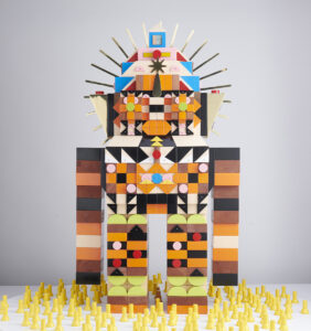 Kumkum Fernando -  <strong>Baby Devis Board Game,</strong> (2023<strong style = 'color:#635a27'></strong>)<bR /> Mixed media - upcycled wood, hand and spray painted wood; scratched coated brass detailing and solid brass halo; recycled nails. Made from 650 blocks. Installation includes 180 hand-turned pawns,
W 25.6 x H 44.2 × D 14.5 inches